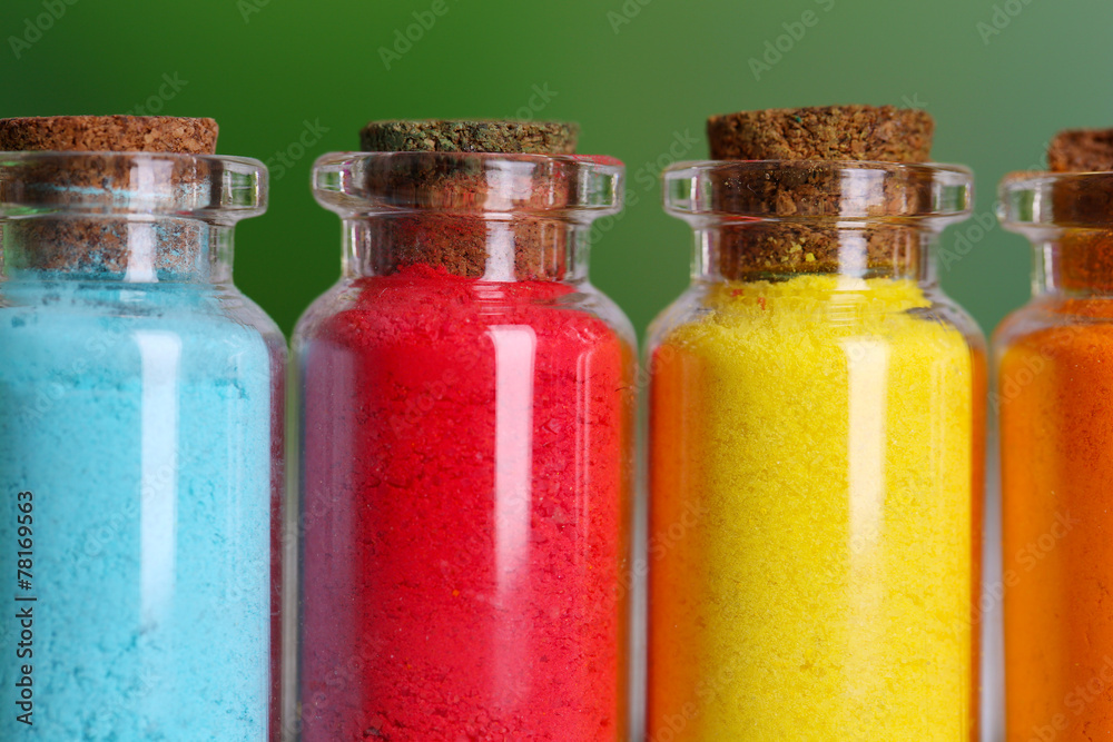 Bottles with colorful dry pigments on bright background