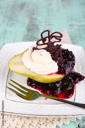 Tasty dessert with pear, cream and berry sauce