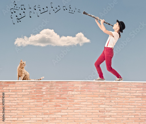 little girl playing clarinet on the top of a bricks wall photo