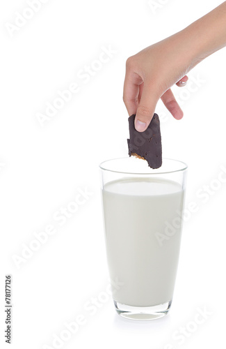 hand holding chocolate biscuits into glass of milk on white back