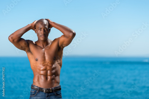 Topless African black man standing on rock