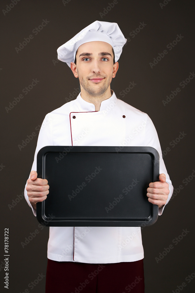 Portrait of chef with oven pan in hands on dark background Portrait of chef with oven pan in hands on dark background