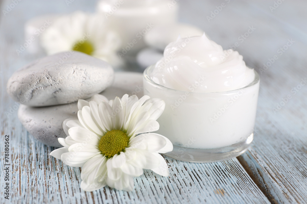 Cosmetic cream with flowers and spa stones on wooden background Cosmetic cream with flowers and spa stones on wooden background