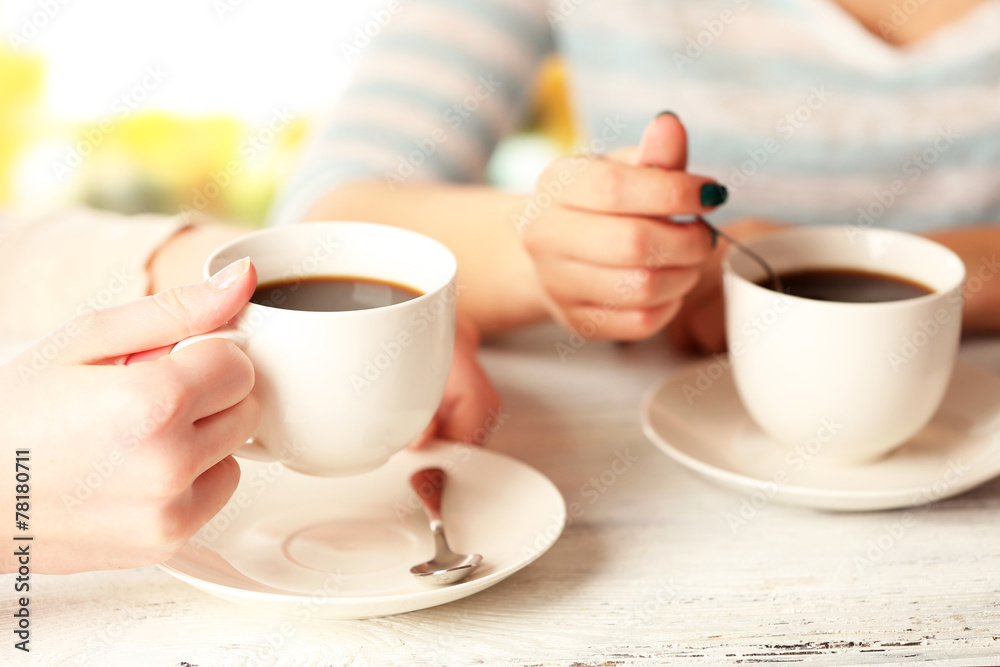 Two women with cups of coffee on bright background Two women with cups of coffee on bright background