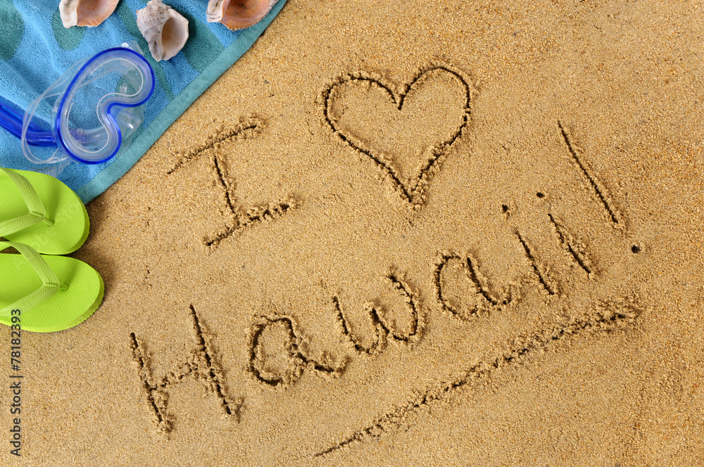 The word I Love Hawaii written in sand on a beach with towel flip flops seashells Hawaiian summer vacation holiday photo