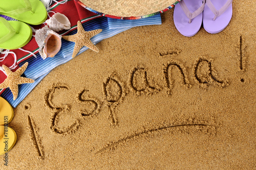 The word Espana written in sand on a beach with towel flip flops seashells Spain summer vacation holiday photo