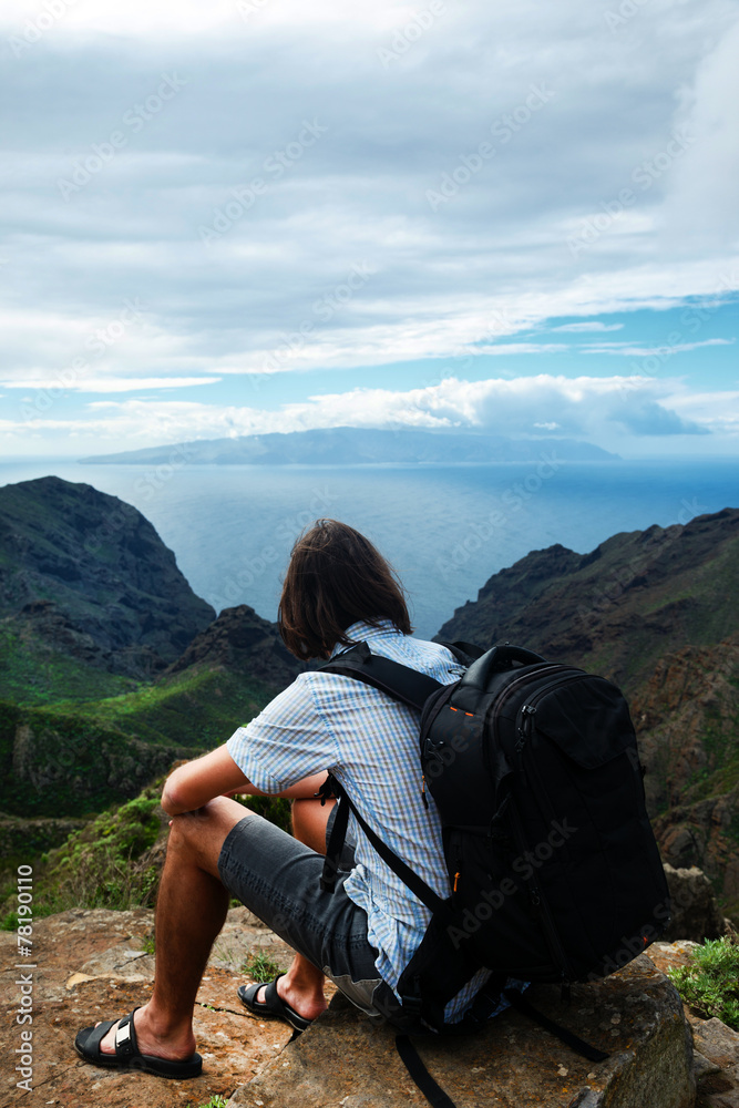 Man sitting on the hill over the mountains and sea
