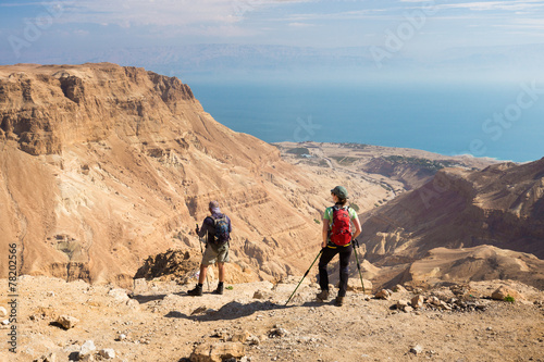 Couple standing desert mountain edge.