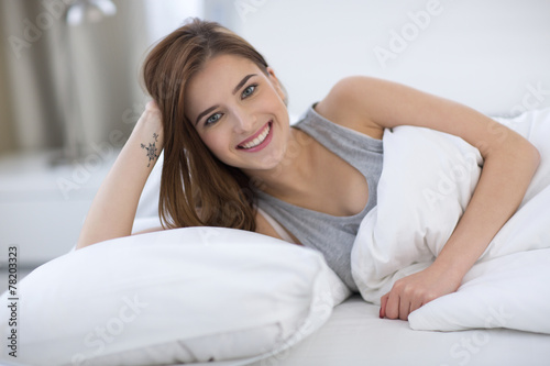 Smiling cute woman lying on the bed at home