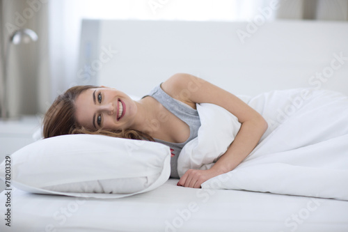 Beautiful happy woman lying on the bed at home