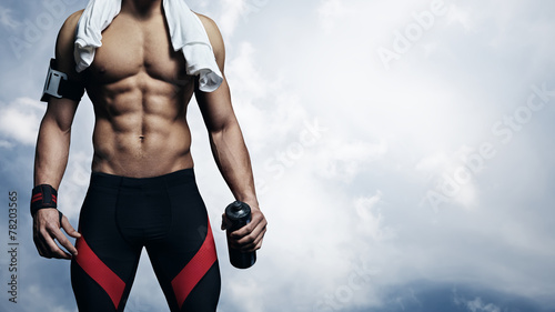 Strong athlete on blue sky background