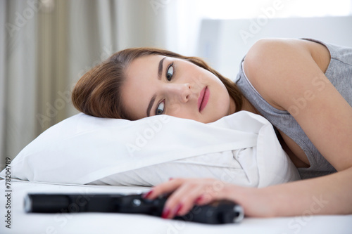 Portrait of a woman lying on the bed with gun