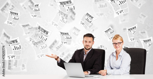 Business man and woman at desk with stock market newspapers