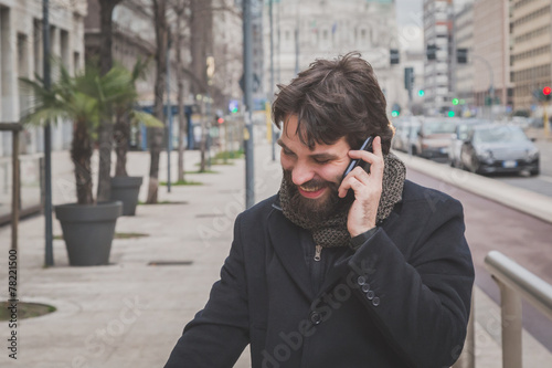 Young handsome bearded man talking on phone