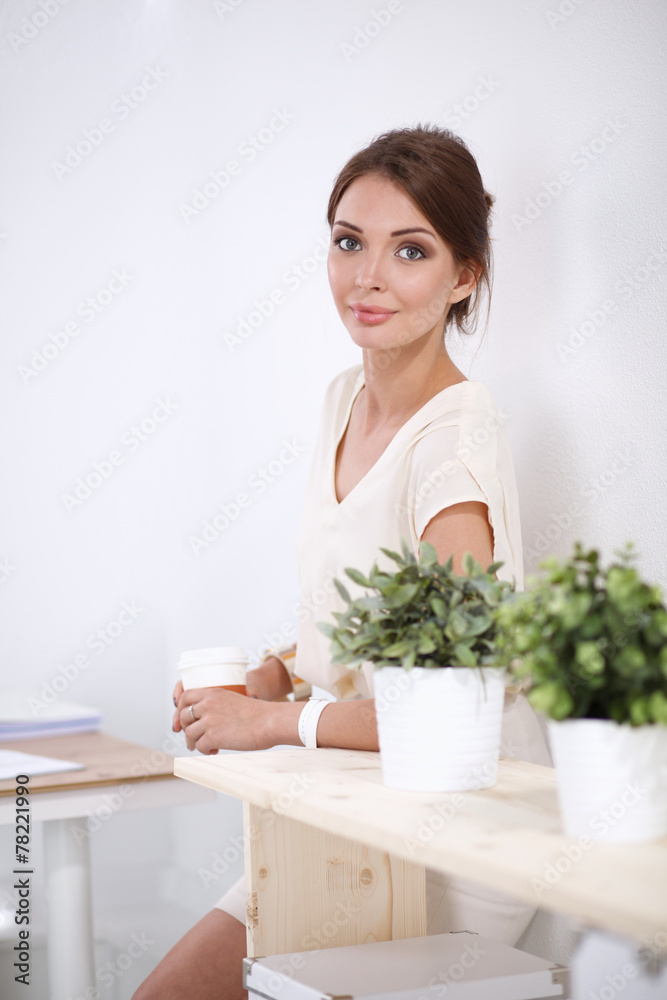 Attractive young businesswoman standing near desk in the office Attractive young businesswoman standing near desk in the office