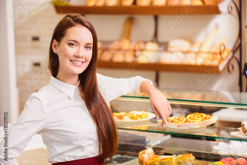 Beautiful young saleswoman in a bakery photo