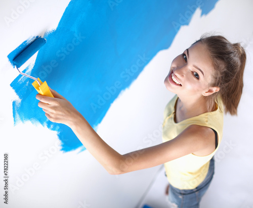 Happy beautiful young woman doing wall painting  standing on