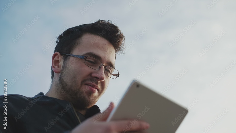 Low angle view of male using tablet PC against sky Low angle view of male using tablet PC against sky