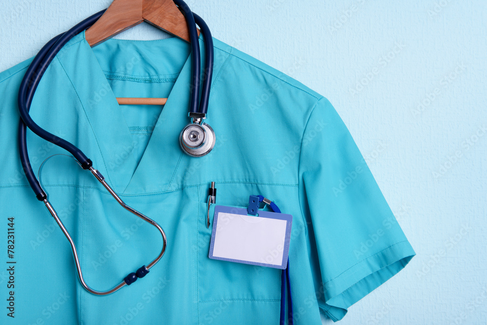 Doctor shirt with stethoscope on hanger on blue background Doctor shirt with stethoscope on hanger on blue background