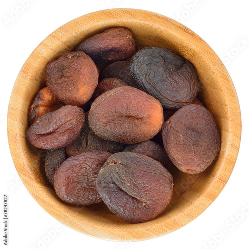 Sun dried apricots in wooden bowl isolated.