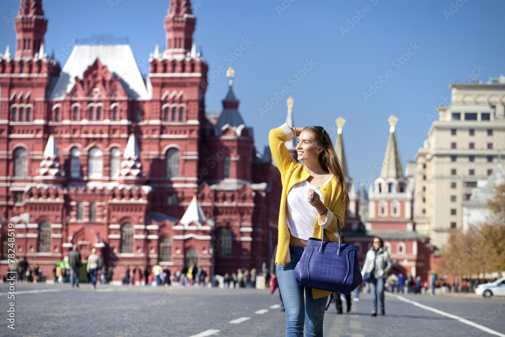 Young woman in yellow coat walks on the Red Square in Moscow