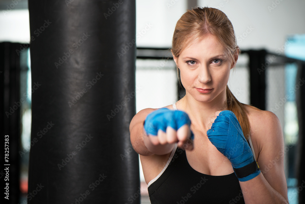 Blonde woman doing martial arts workout in a gym