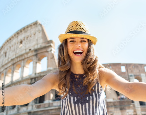Happy young woman making selfie in front of colosseum in rome