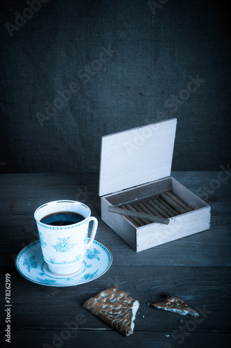 Cup of coffee, biscuits and a box of cigarettes on old wooden ta