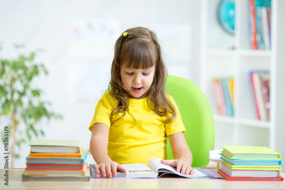 child reading book at table in nursery child reading book at table in nursery