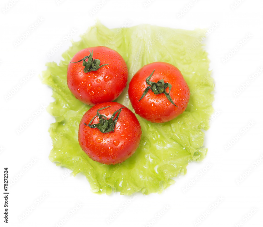 Three tomatoes lying on a sheet of green salad Three tomatoes lying on a sheet of green salad