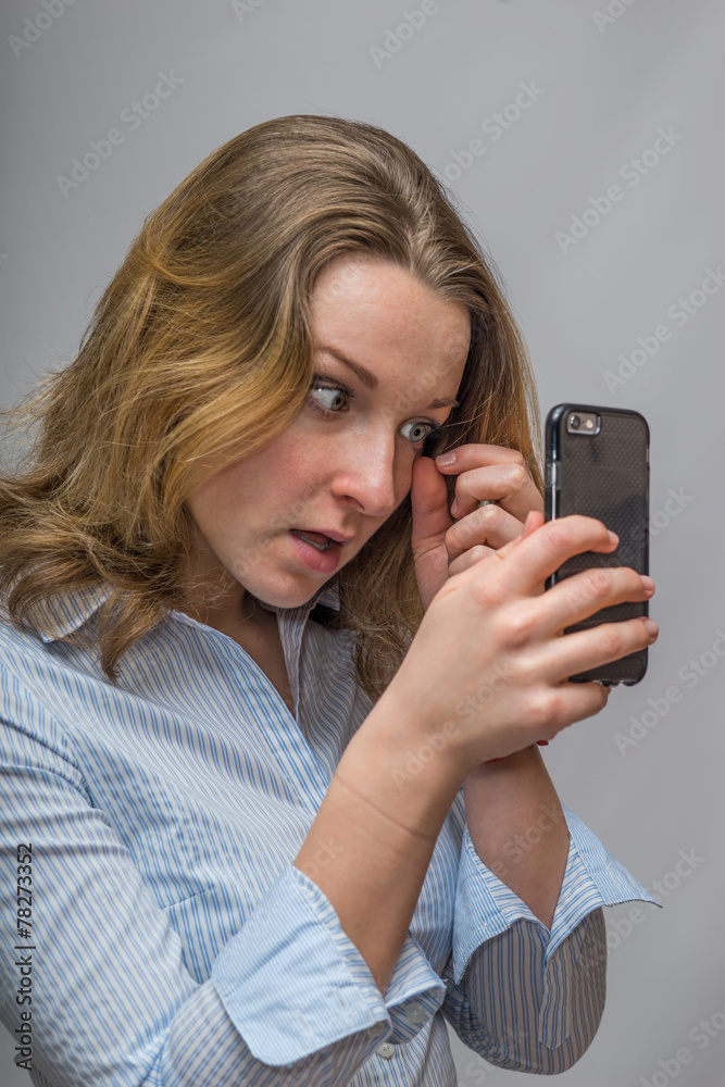 Business Woman fixing eye make up in the cell phone camera