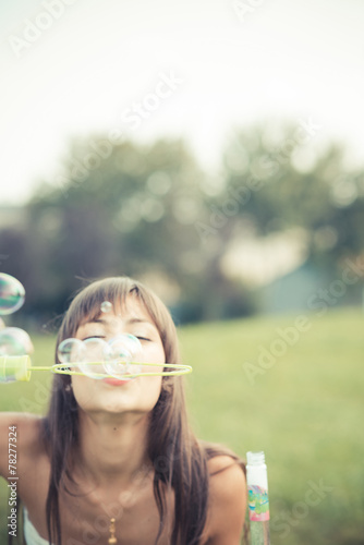 beautiful young woman with white dress blowing bubble