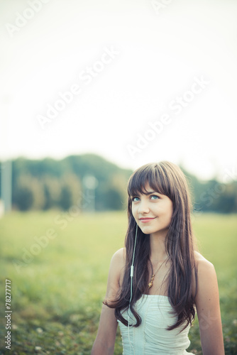 beautiful young woman with white dress listening music