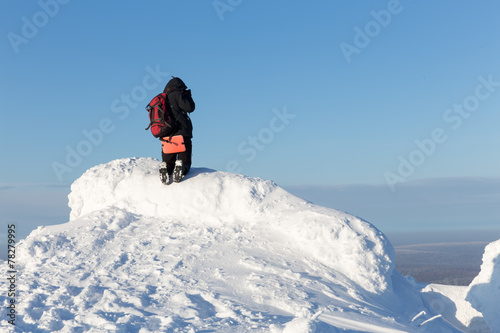 Tourist on a snowy mountain top against the blue sky