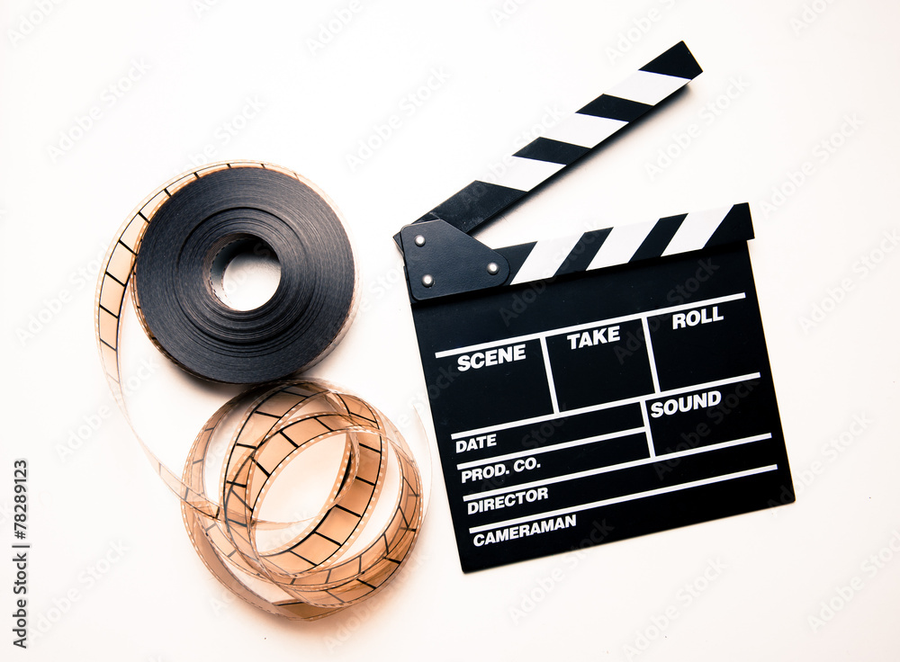 Unrolled 35mm movie reel and clapperboard in vintage color effec Stock  Photo
