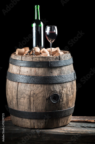 Glass of wine and bottle on old oak barrel