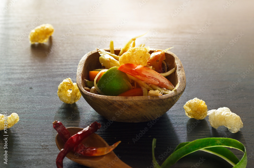 papaya salad in wood bowl and cristy pork on wooden papaya salad in wood bowl and cristy pork on wooden