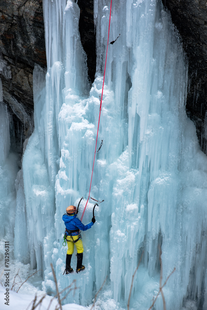 Brave ice climber climbing a iced waterfall in italian alps