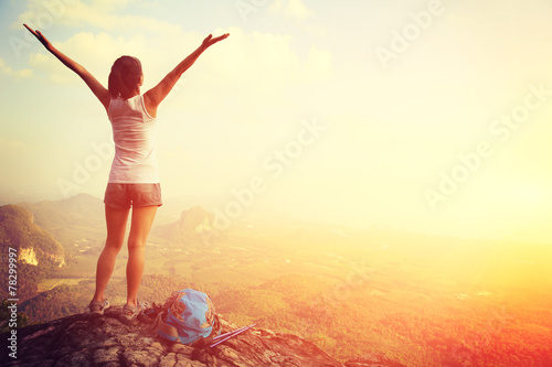 	strong confident woman hiker open arms at on mountain peak rock photo