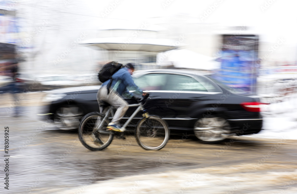 Man on bicycle in the city in a snowy day.