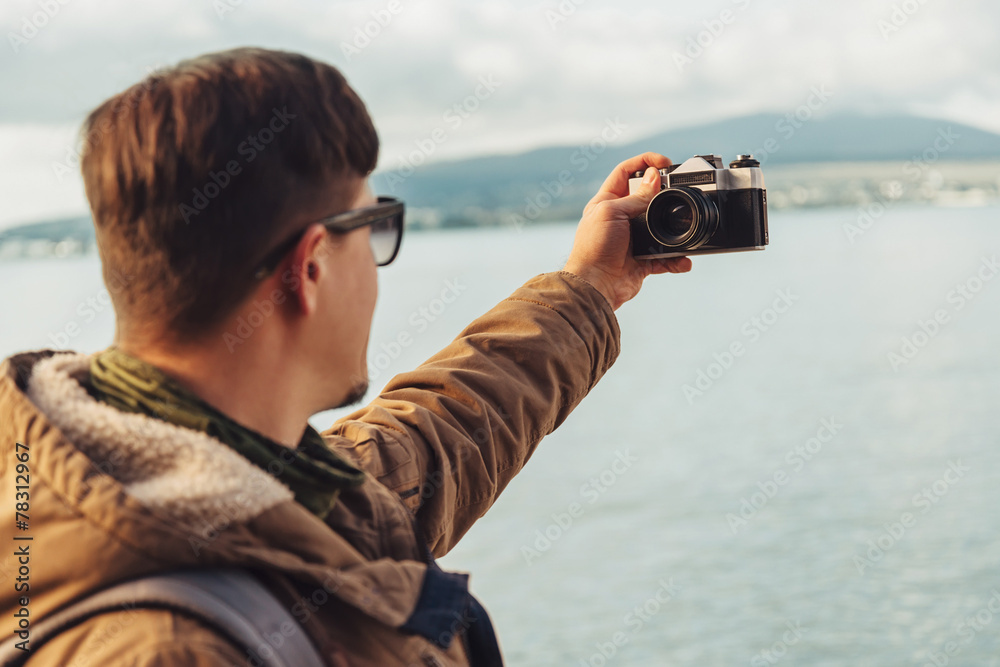 Obraz premium Young man takes photographs self-portrait on coast