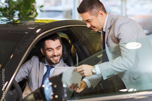 happy man with car dealer in auto show or salon