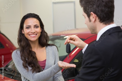 Businessman giving car key while shaking a customer hand