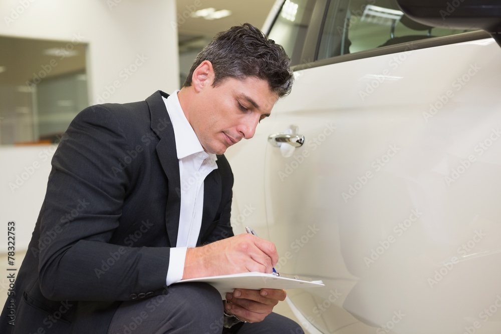 Focused businessman looking at the car body
