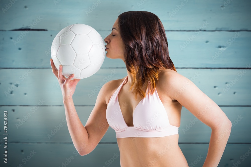 Composite image of brunette in bikini kissing football Composite image of brunette in bikini kissing football