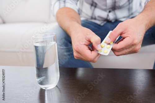 Fotografie Hungover man with his medicine laid out on coffee table