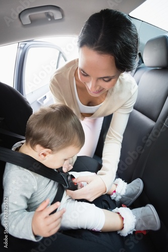 Mother securing her baby in the car seat