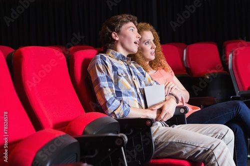 Astonished young couple watching a film