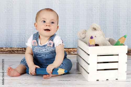 Laughing little baby girl with big pencils