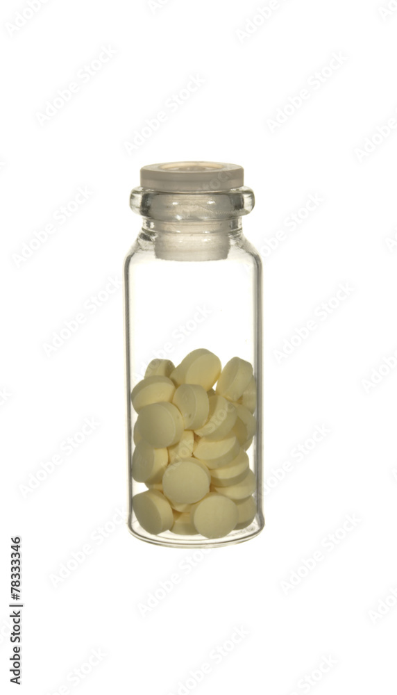 Transparent glass bottle of yellow pills isolated on a white bac Transparent glass bottle of yellow pills isolated on a white bac